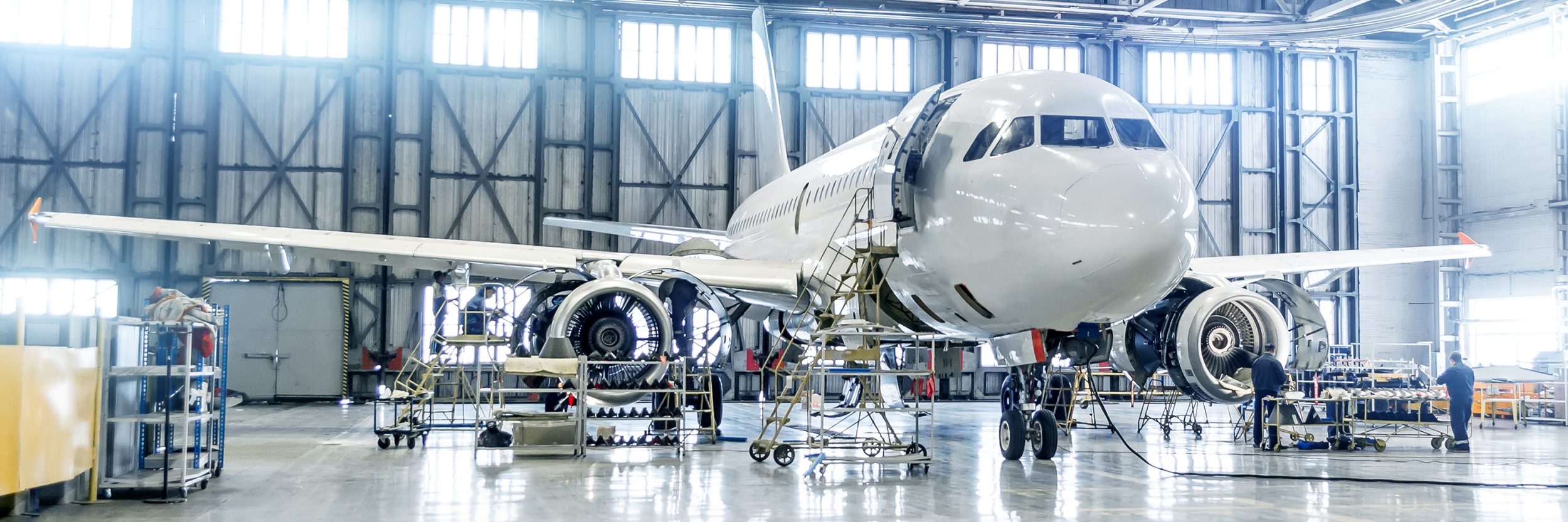 Large aeroplane in hanger, surrounded by technicians as it's worked on