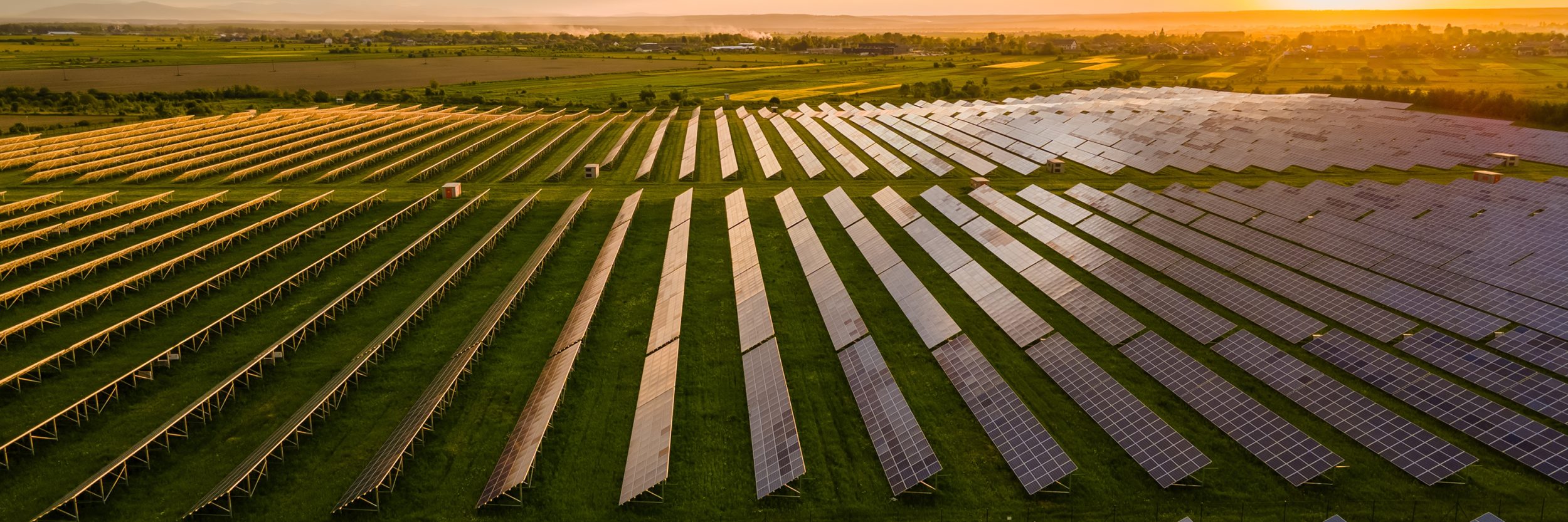 Rolling fields of solar panels with the sun setting in the background