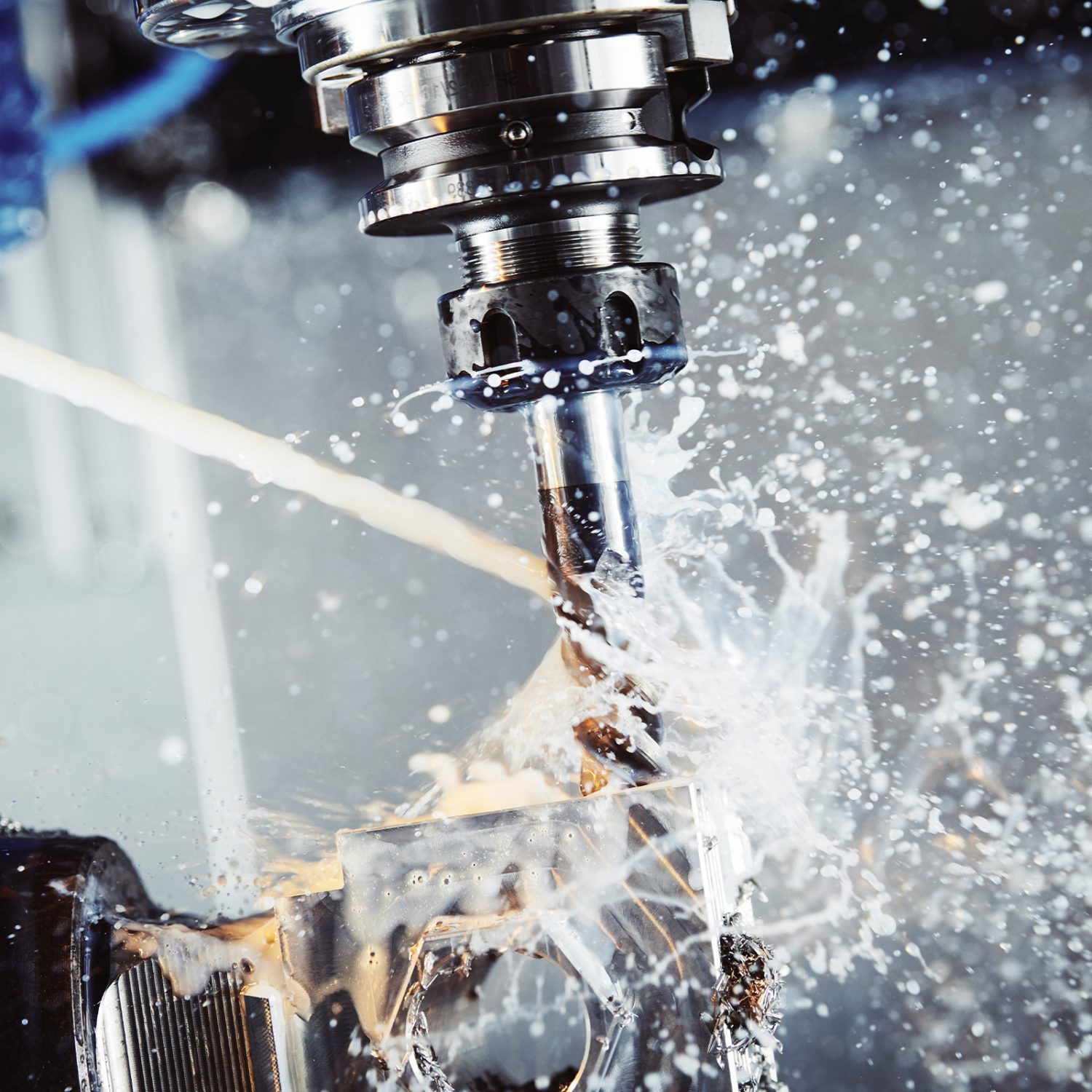 Milling machine boring into metal block with steam and water splashing