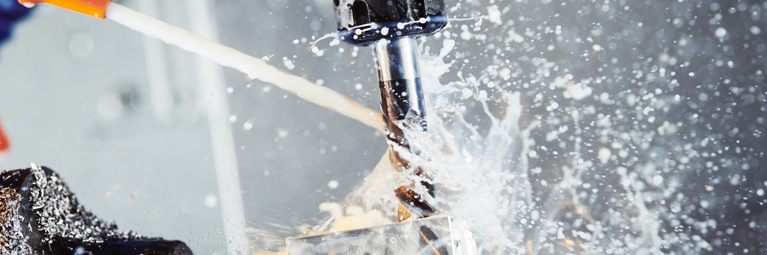 Milling machine boring into metal block with steam and water splashing