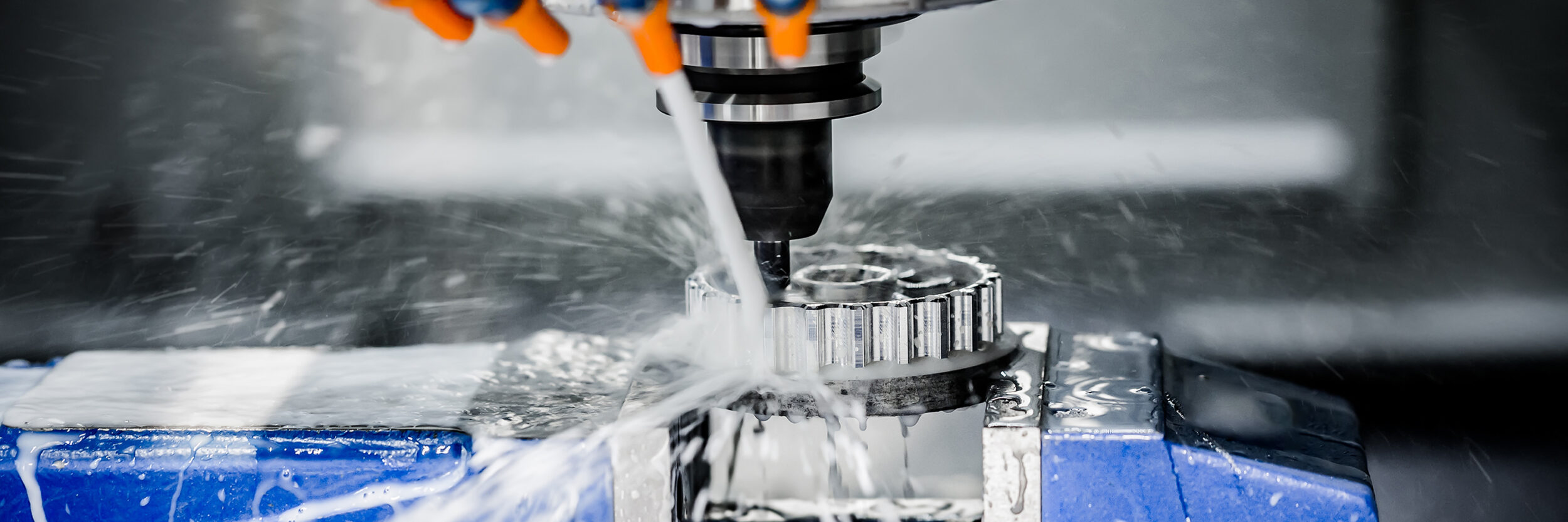 Milling machine boring into metal block with steam and water splashing